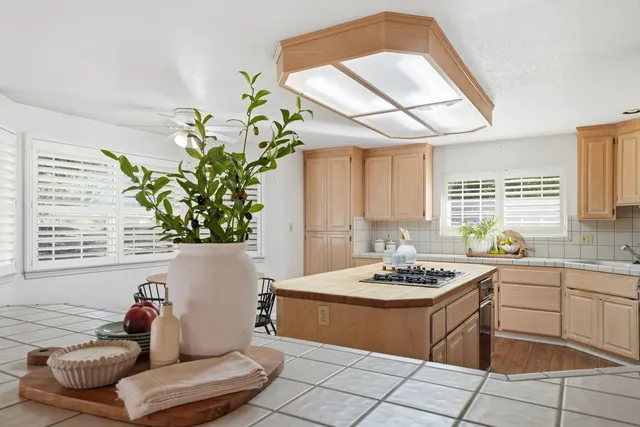 a kitchen with kitchen island granite countertop a table chairs sink and cabinets