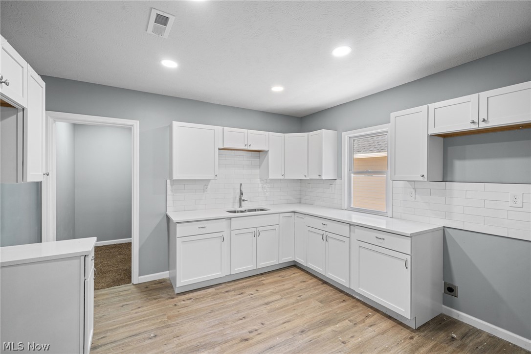 3925 Riverside Avenue Cleveland, OH 44109 - Photo 26 of 48 Kitchen featuring recessed lighting, white shaker-style cabinetry, a stainless steel sink with a gooseneck faucet, white subway tile backsplash, and wood-finish flooring