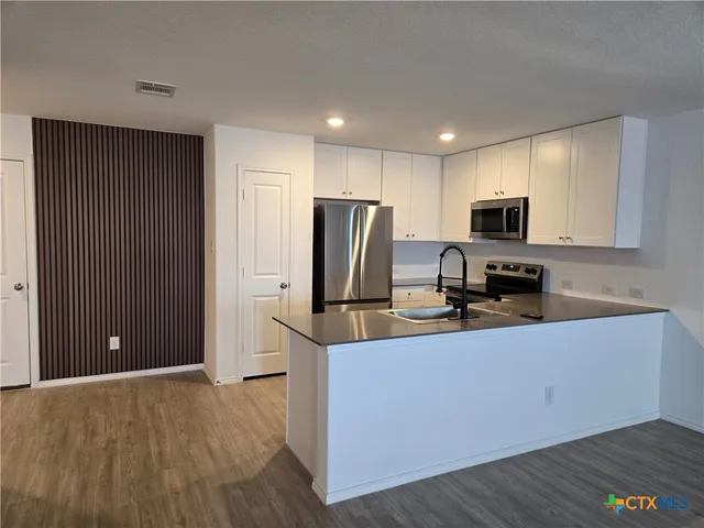 a kitchen with kitchen island a counter top space cabinets and stainless steel appliances