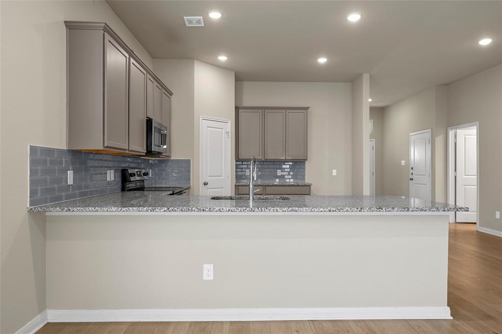 3205 Dottavio Road Lorena, TX 76655 - Photo 8 of 33 Kitchen featuring a large breakfast bar with speckled countertop, gray subway tile backsplash, and light gray cabinetry