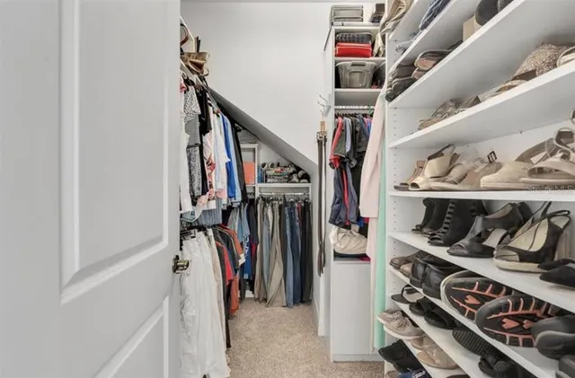 a view of walk in closet with clothes and shoes