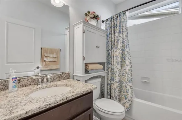 a bathroom with a granite countertop sink toilet and shower