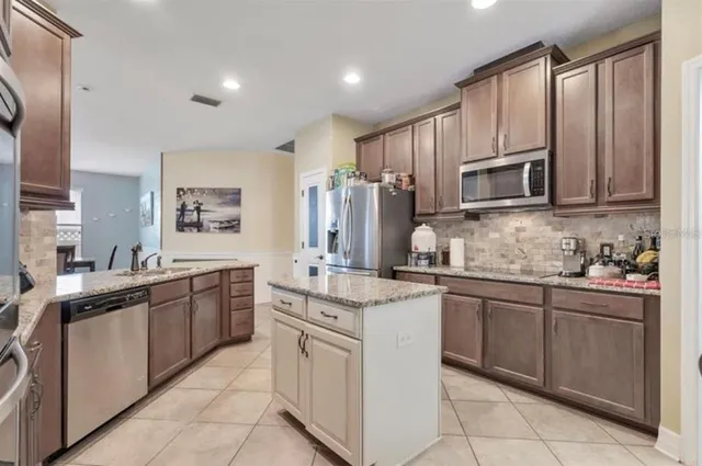 a kitchen with stainless steel appliances granite countertop a stove top oven a sink dishwasher and a refrigerator