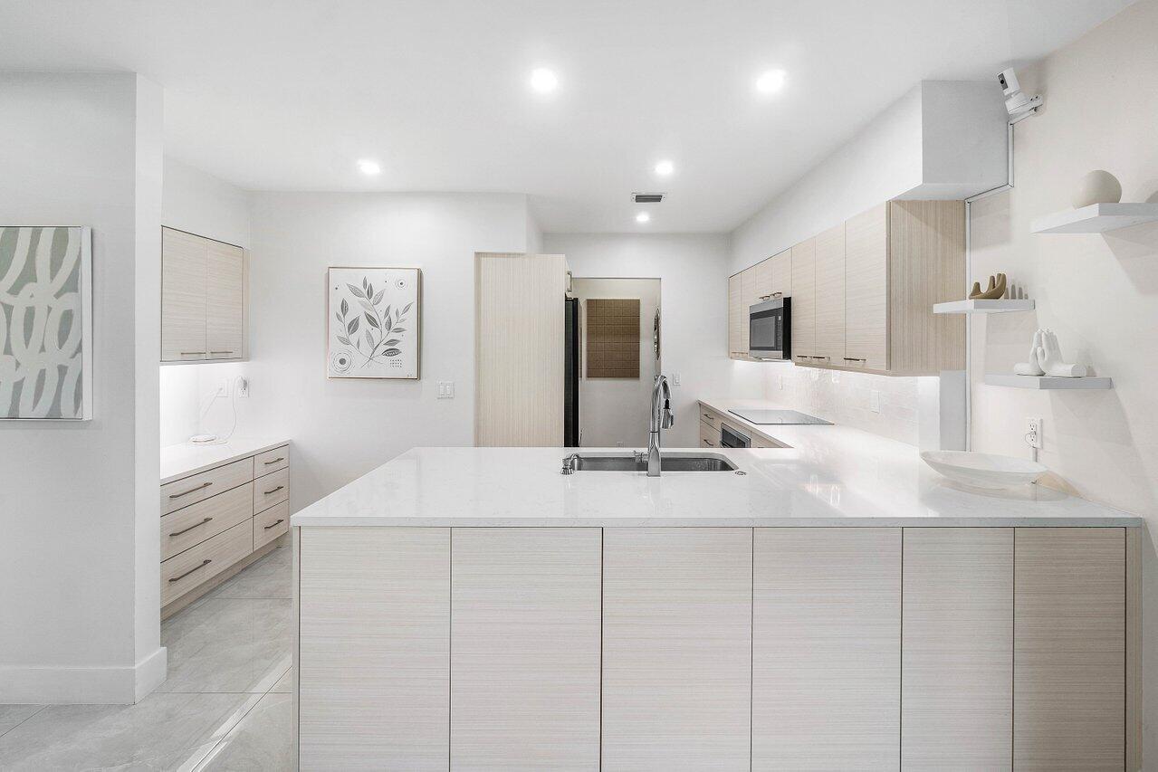 19173 Sabal Lake Drive, Unit 5155 Boca Raton, FL 33434 - Photo 9 of 33 a large white kitchen with kitchen island a sink stainless steel appliances and cabinets