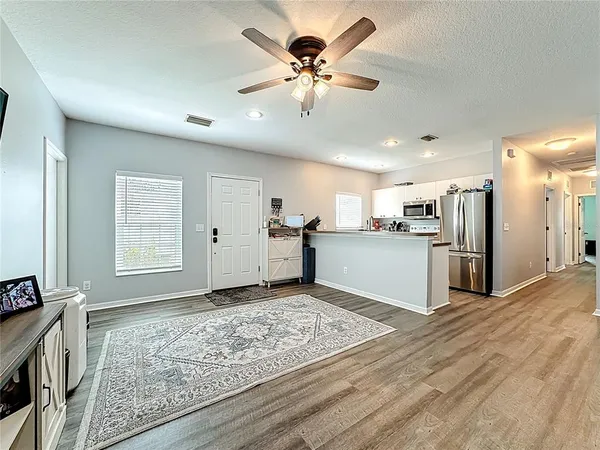 a view of an empty room with kitchen and a window