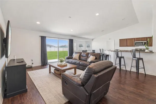 a kitchen with stainless steel appliances kitchen island granite countertop a dining table chairs and a refrigerator