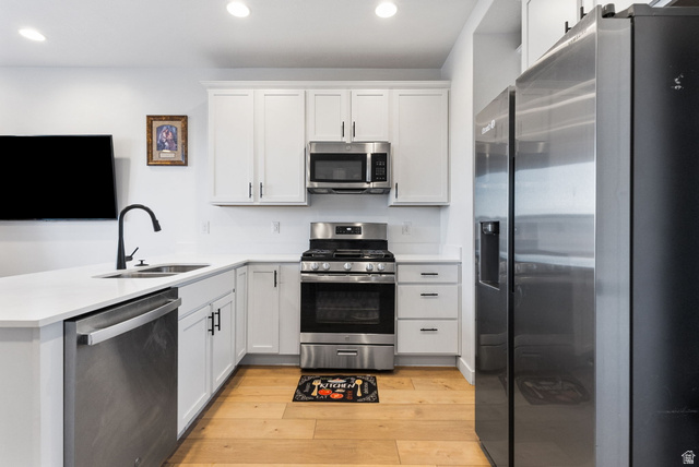 3473 Hardman Way Lehi, UT 84048 - Photo 10 of 22 Kitchen with stainless steel appliances, white cabinets, a peninsula, light wood finished floors, and recessed lighting