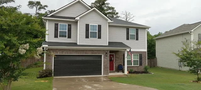 a front view of a house with a garden and yard