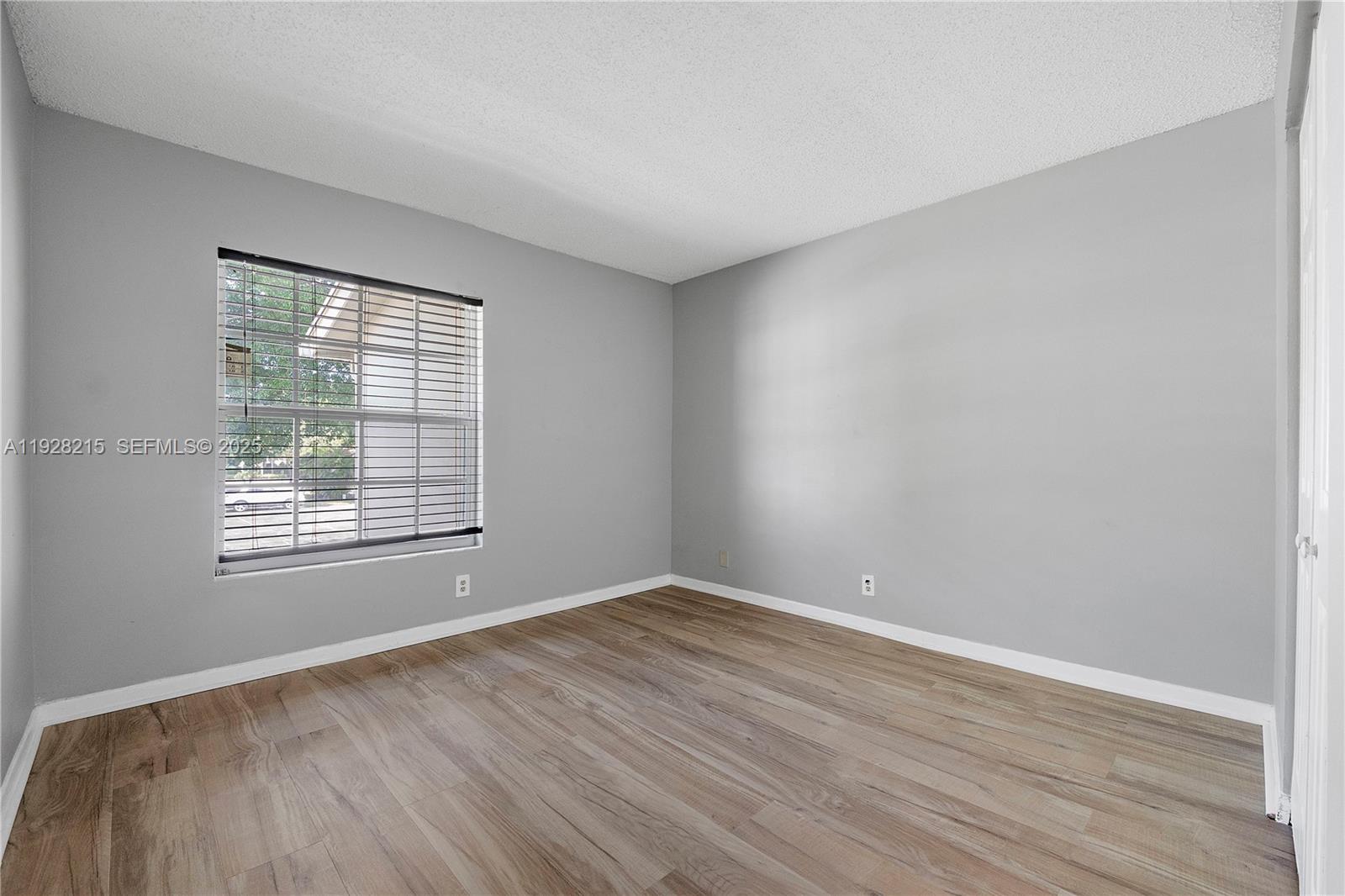 5850 Northwest 57th Avenue, Unit 1 Tamarac, FL 33319 - Photo 32 of 56 a view of an empty room with wooden floor and a window
