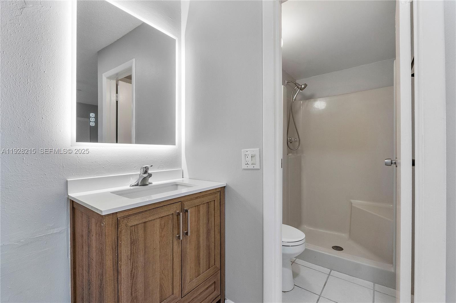 5850 Northwest 57th Avenue, Unit 1 Tamarac, FL 33319 - Photo 36 of 56 a bathroom with a granite countertop sink toilet a mirror and shower