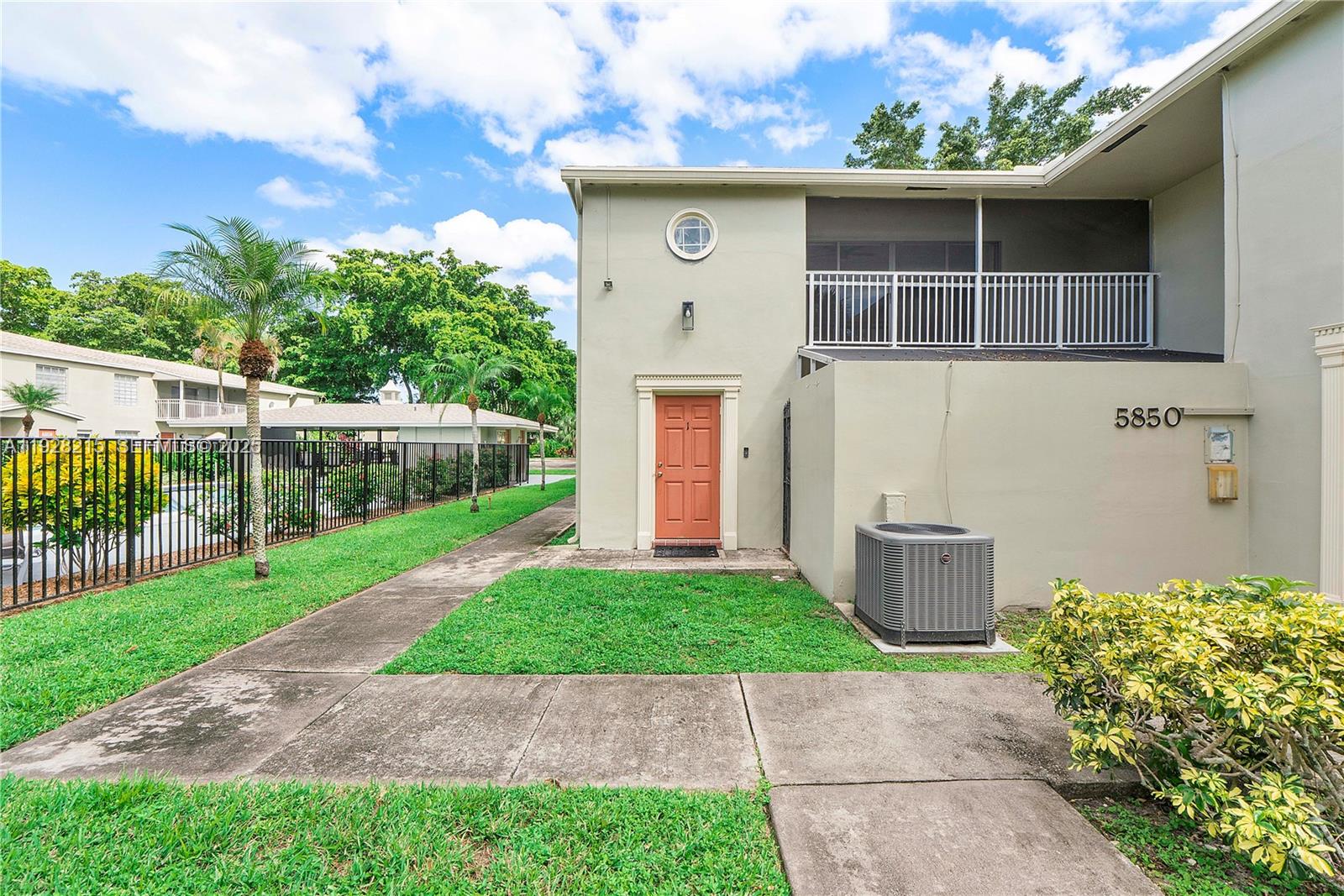 5850 Northwest 57th Avenue, Unit 1 Tamarac, FL 33319 - Photo 52 of 56 a front view of a house with a yard and potted plants