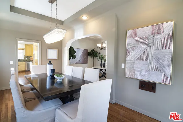 a dining room with wooden floor a chandelier a glass table and chairs