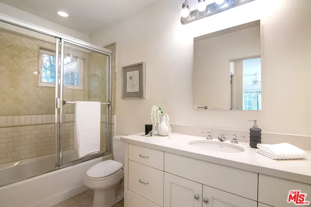 a bathroom with a granite countertop sink toilet mirror and shower