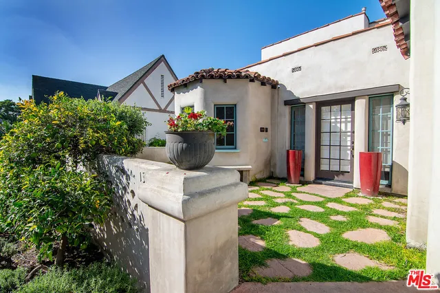 a view of a house with potted plants and floor to ceiling window