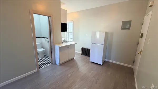 an empty room with wooden floor and cabinet
