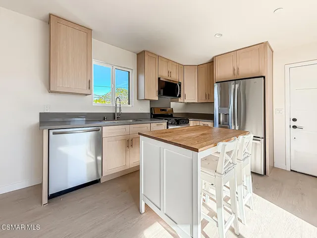 a kitchen with stainless steel appliances a stove refrigerator sink and microwave