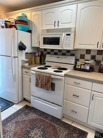 a kitchen with white cabinets and appliances
