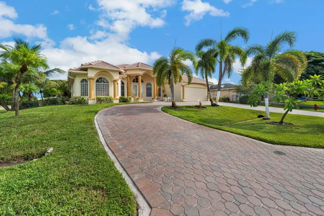 a front view of a house with a yard and palm trees
