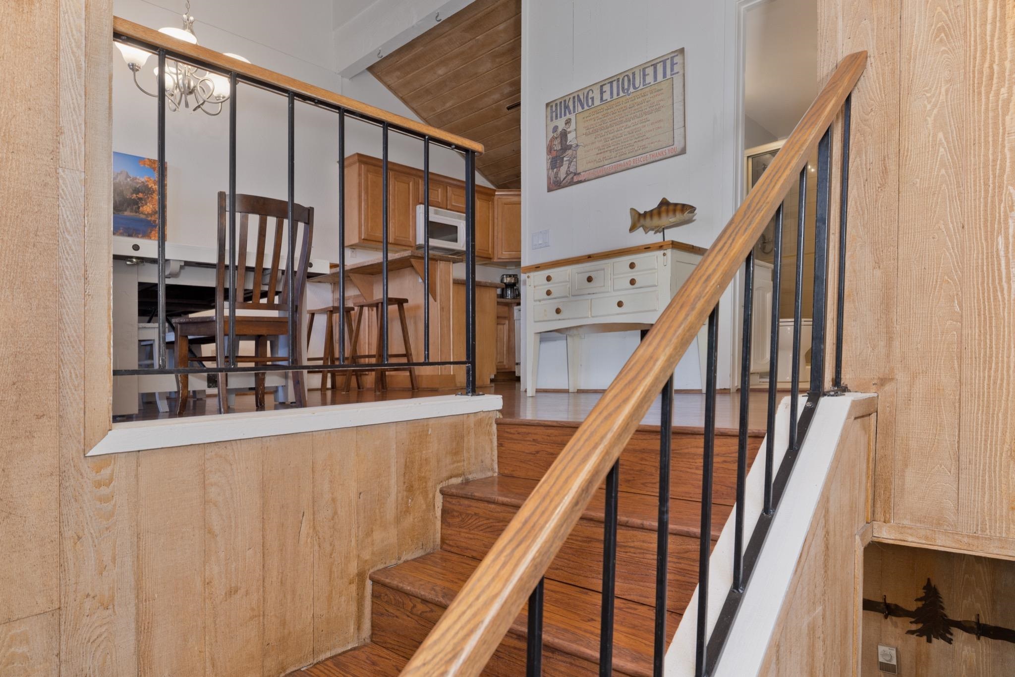 3392 Chateau Road, Unit 29 Mammoth Lakes, CA 93546 - Photo 4 of 30 Hardwood staircase with black metal balusters and a wood-finish handrail, complemented by wood-paneled walls