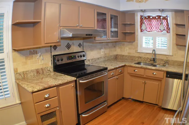 a kitchen with granite countertop a sink cabinets and stainless steel appliances