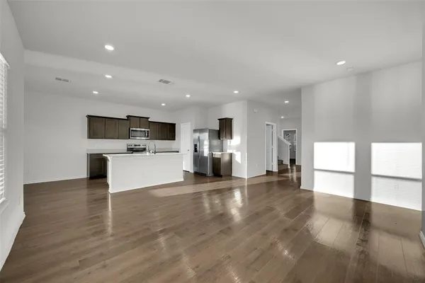 a view of a big room with wooden floor and windows