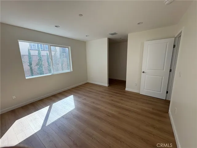 a view of an empty room with wooden floor and closet