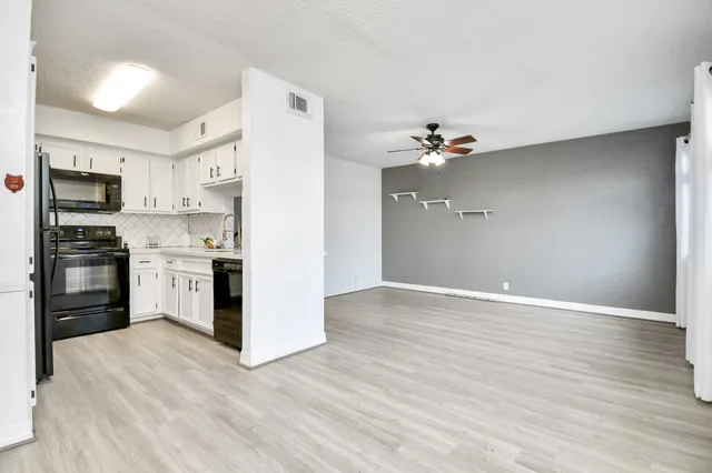 a view of a kitchen with a sink a ceiling fan and stainless steel appliances