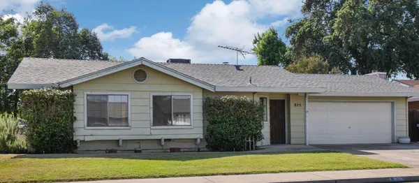 a view of a house with a yard and large tree