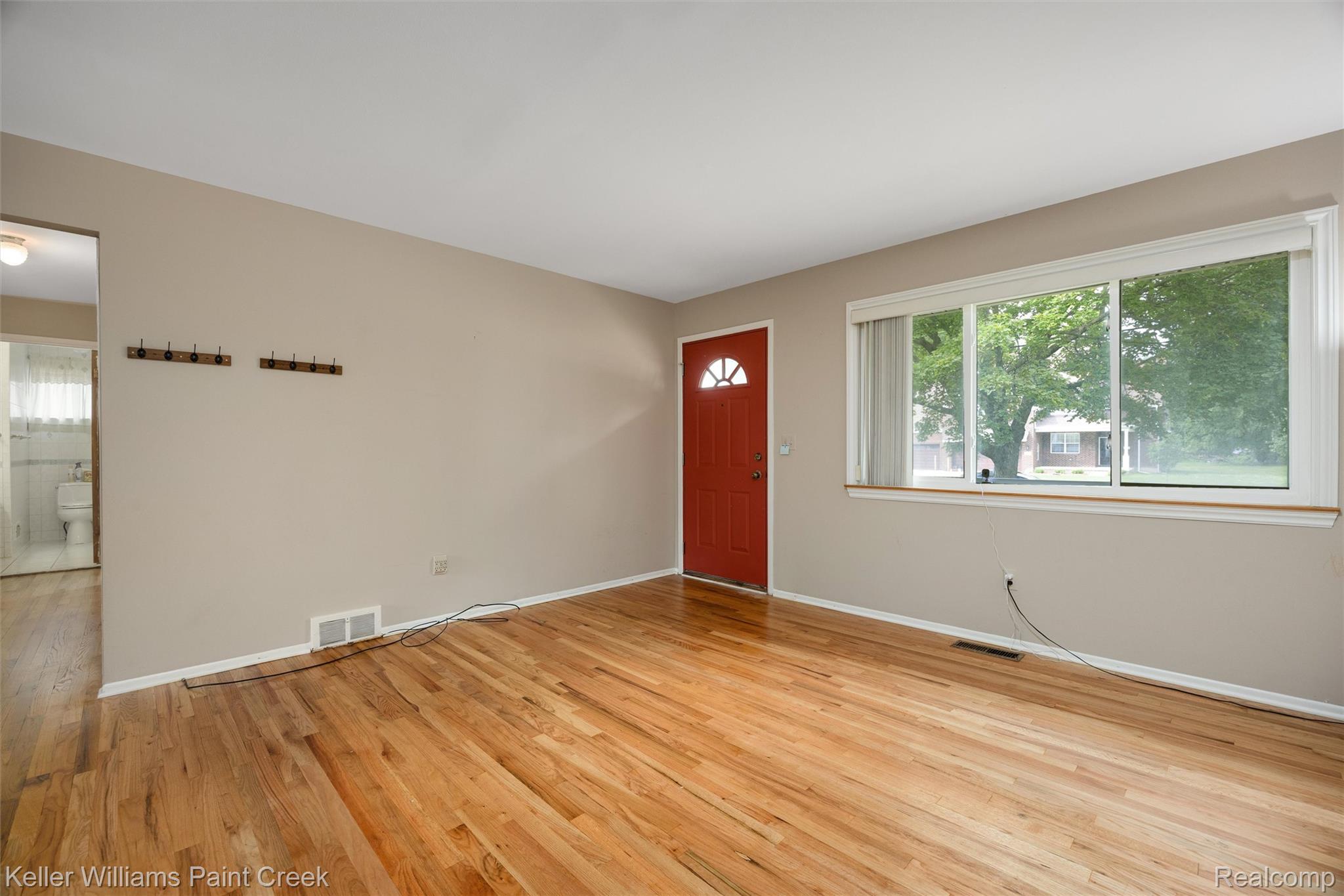 1766 Henry Ruff Road Garden City, MI 48135 - Photo 2 of 36 Hardwood flooring throughout, neutral wall paint, red entryway door, and a large multi-pane window