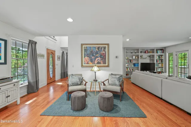 a living room with furniture a large window and wooden floor