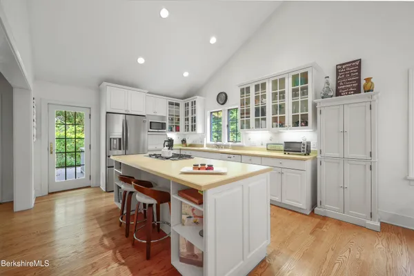a kitchen with stainless steel appliances granite countertop a stove a refrigerator a sink dishwasher and a dining table with wooden floor