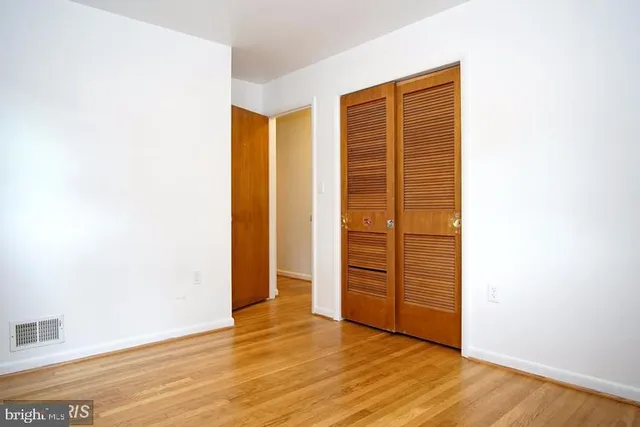 an empty room with wooden floor and closet