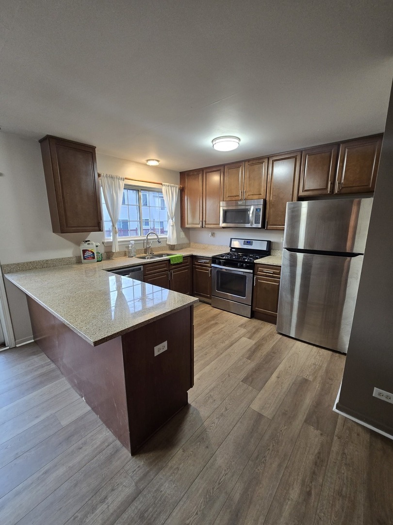 647 Georgian Court, Unit 647 Addison, IL 60101 - Photo 2 of 12 a kitchen with wooden cabinets a sink and a stove