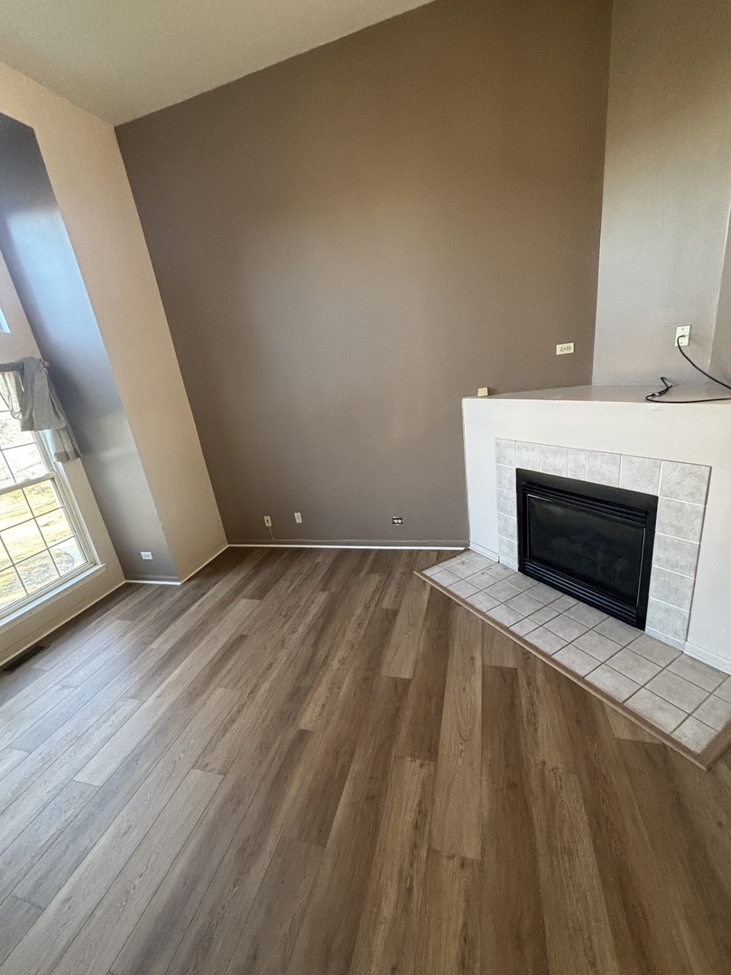 647 Georgian Court, Unit 647 Addison, IL 60101 - Photo 5 of 12 a view of empty room with wooden floor and fireplace