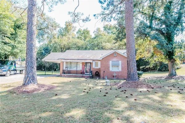 a view of a house with a yard and large tree