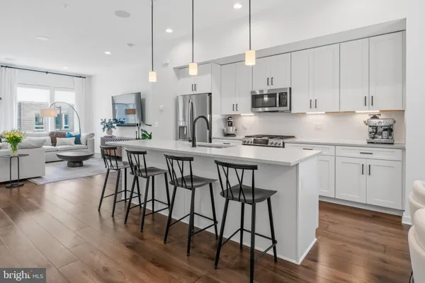 a kitchen with stainless steel appliances kitchen island granite countertop a table chairs stove and white cabinets