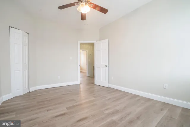 an empty room with wooden floor chandelier fan and window