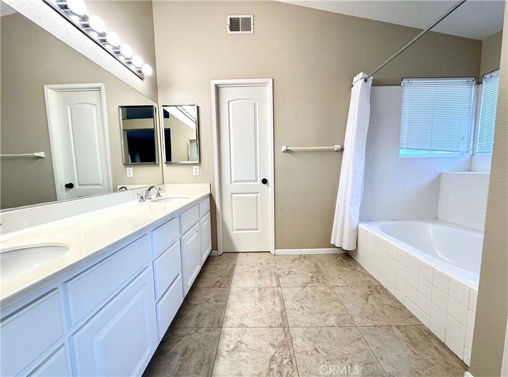 16208 Peppertree Lane La Mirada, CA 90638 - Photo 35 of 75 a bathroom with a double vanity sink a large mirror and a bathtub