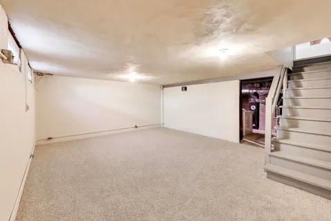 a view of an empty room with stairs and a window