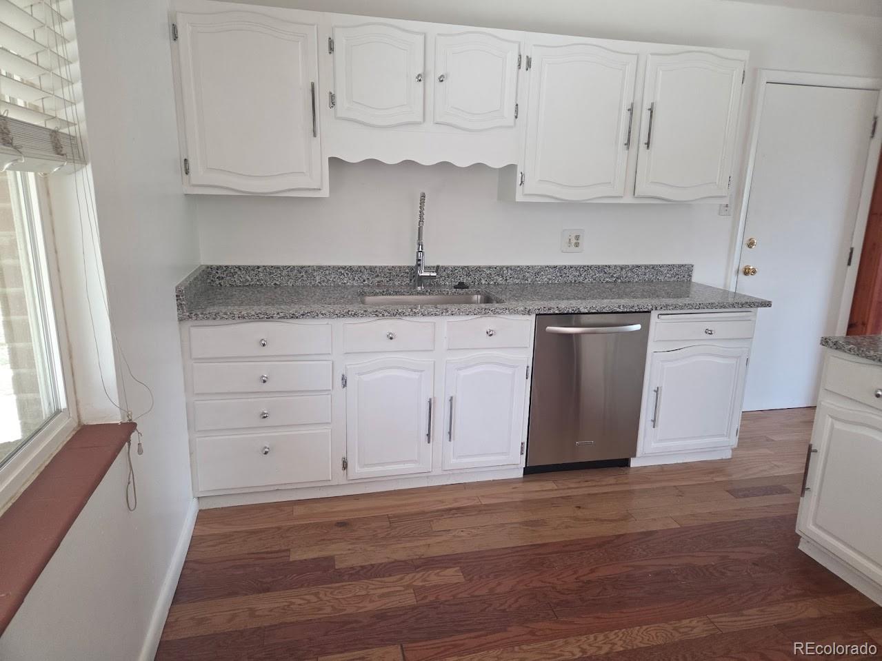 2771 South Perry Street Denver, CO 80236 - Photo 5 of 40 a kitchen with granite countertop white cabinets and stainless steel appliances