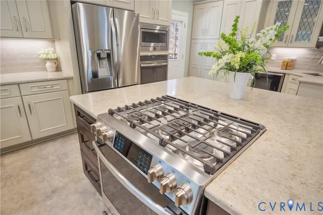 a kitchen with stainless steel appliances granite countertop a refrigerator a stove and a sink