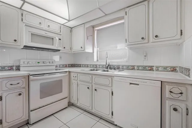 a kitchen with granite countertop white cabinets and white appliances