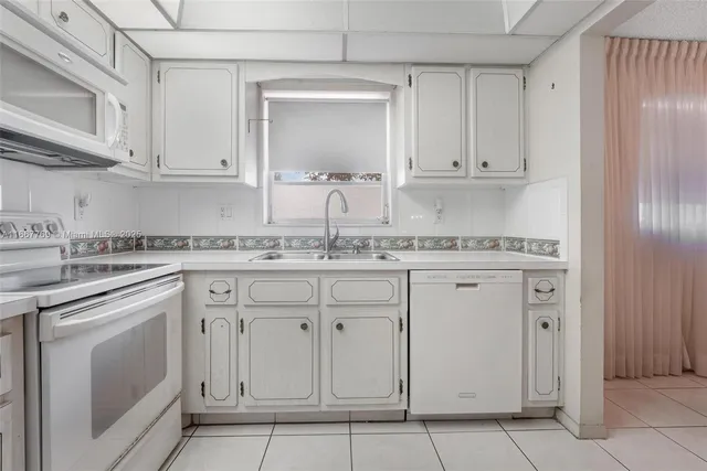 a kitchen with stainless steel appliances granite countertop a sink and dishwasher with white cabinets