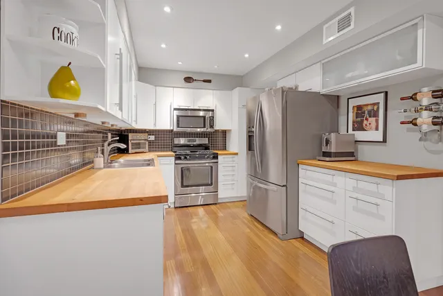 a kitchen with stainless steel appliances a stove a sink a microwave a refrigerator and cabinets