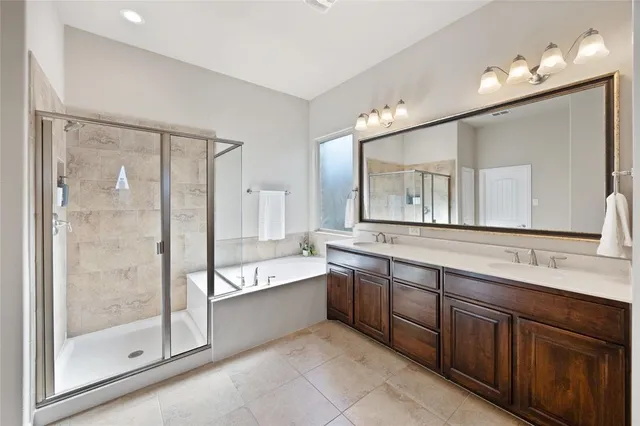 a bathroom with a bathtub shower sink double vanity and mirror