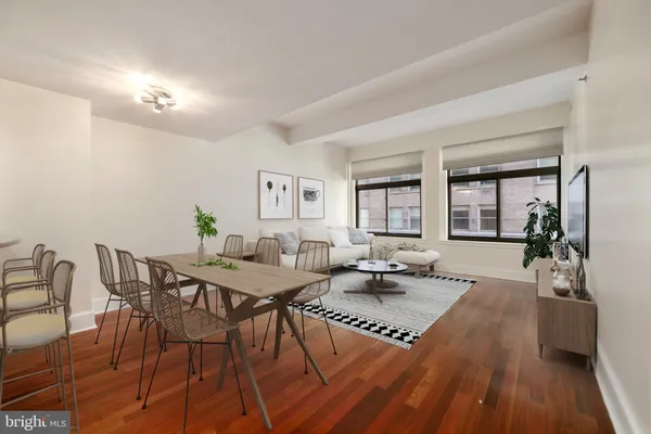 a living room with dining table a rug potted plant and kitchen view