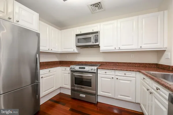 a kitchen with granite countertop white cabinets and stainless steel appliances
