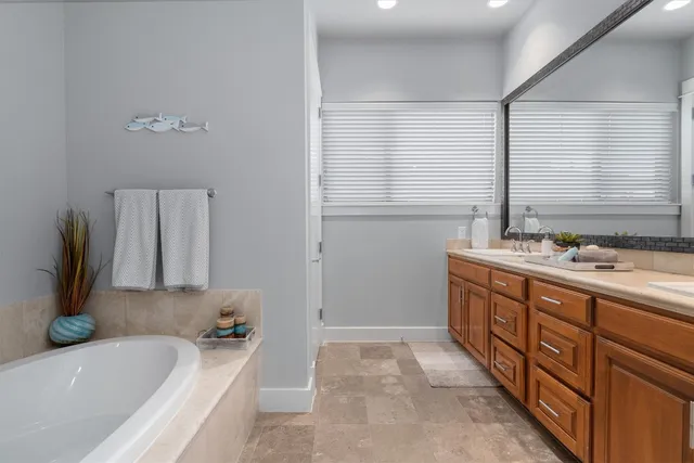 a bathroom with a granite countertop tub sink and mirror