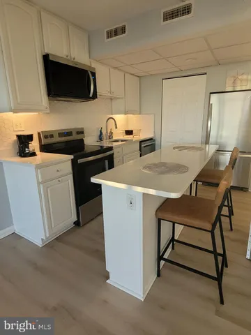 a kitchen with a table chairs a stove a microwave and cabinets