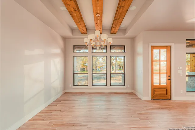 a view of an empty room with wooden floor and fan